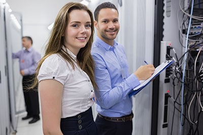 Two smiling technicians checking the servers in data center